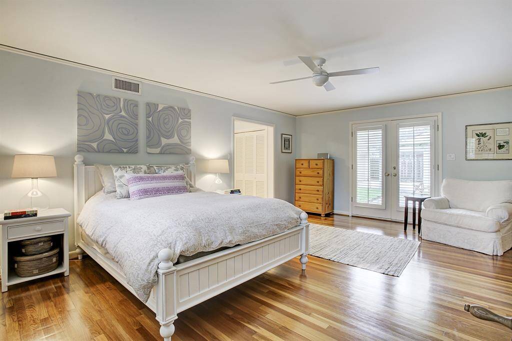 Enormous Primary Bedroom with gleaming hardwood floors & French Doors to back yard & covered patio.
