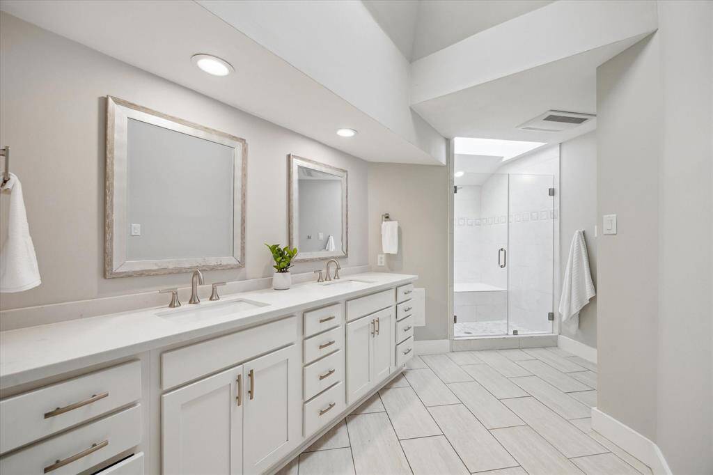 Bathed in natural light from the overhead skylights, the ensuite offers abundant counter space, thoughtful storage, and a private shower retreat complete with a built-in bench.