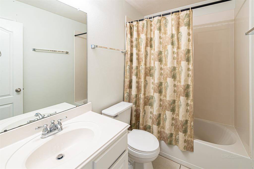 A full bath, positioned between the two secondary bedrooms, offers both convenience and added storage via the linen closet, located behind the open door.
