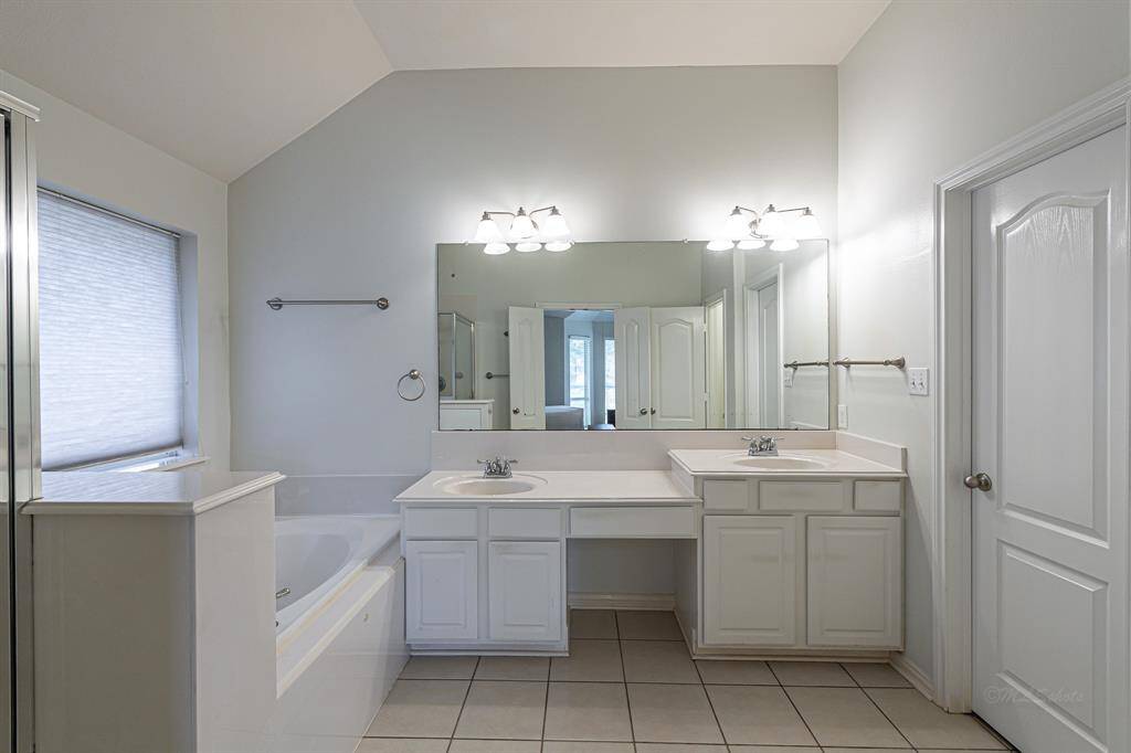 The spacious primary bath includes dual sinks, a vanity area, a soaking tub, a separate shower, and a private commode area.