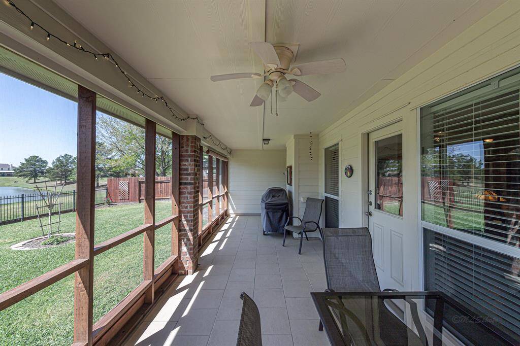 The expansive, tiled, screened-in patio, illuminated by ambient lighting and cooled by a ceiling fan, offers an ideal outdoor living space with tranquil pond and nature views.