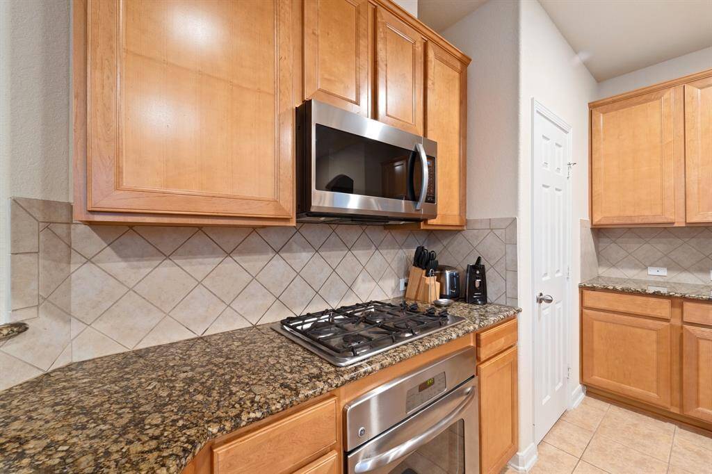 Close-up of the kitchen workspace with gas cooktop, built-in microwave, and abundant cabinet storage.