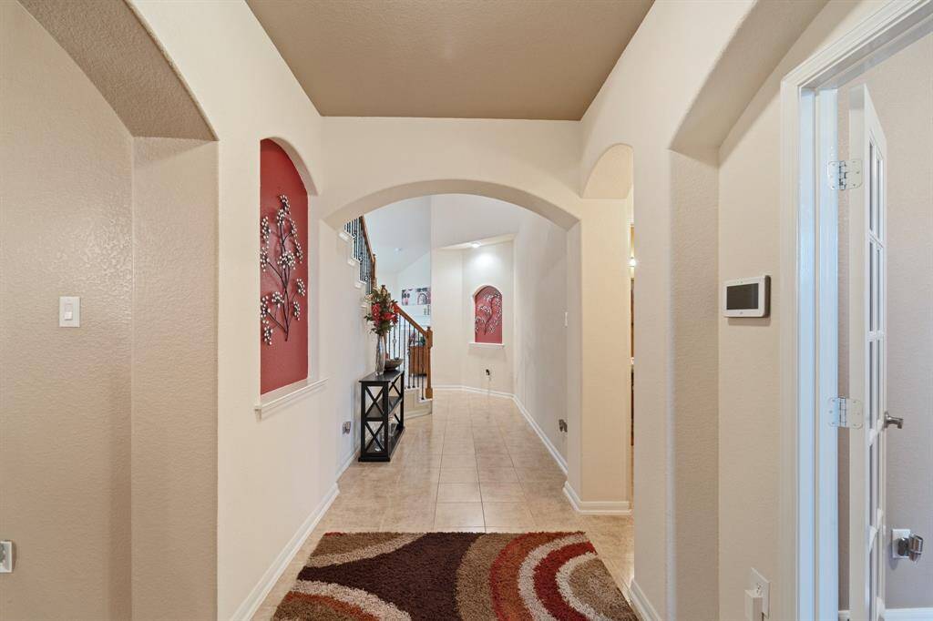 Welcoming foyer with arched doorways, decorative niches, and sightlines to the staircase and living room beyond.