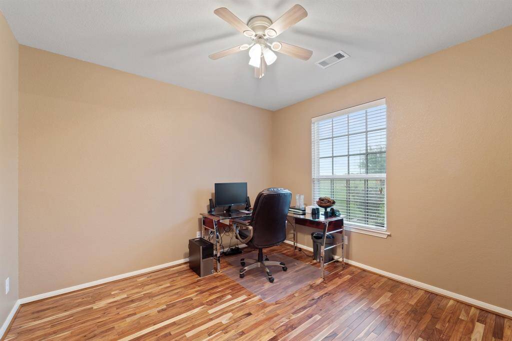 Bright and versatile room with wood flooring and large window—perfect as a home office, study, or flex space.