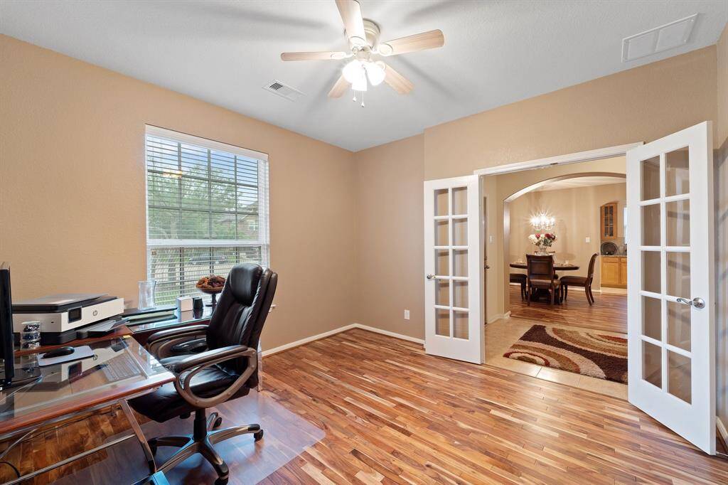 French doors open into this private study, offering a quiet retreat with natural light and views into the formal dining area.