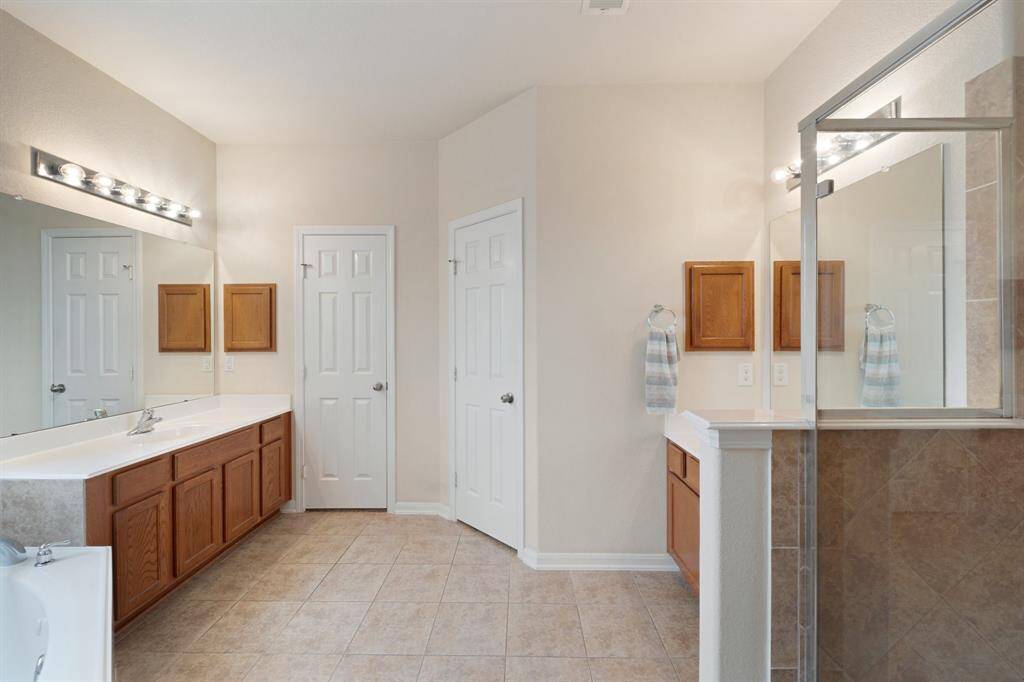 Primary bathroom offers dual vanities, abundant counter space, and access to the walk-in closet and private water closet.