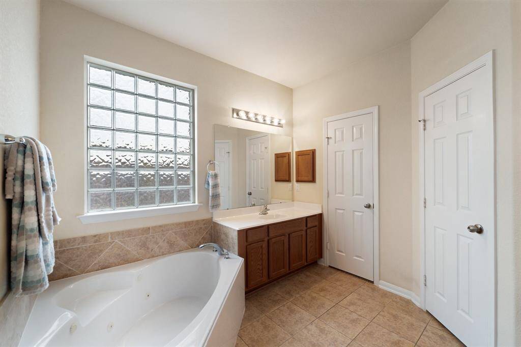 Soaking tub sits beneath a frosted glass block window for privacy and light, creating a spa-like retreat in your own home.