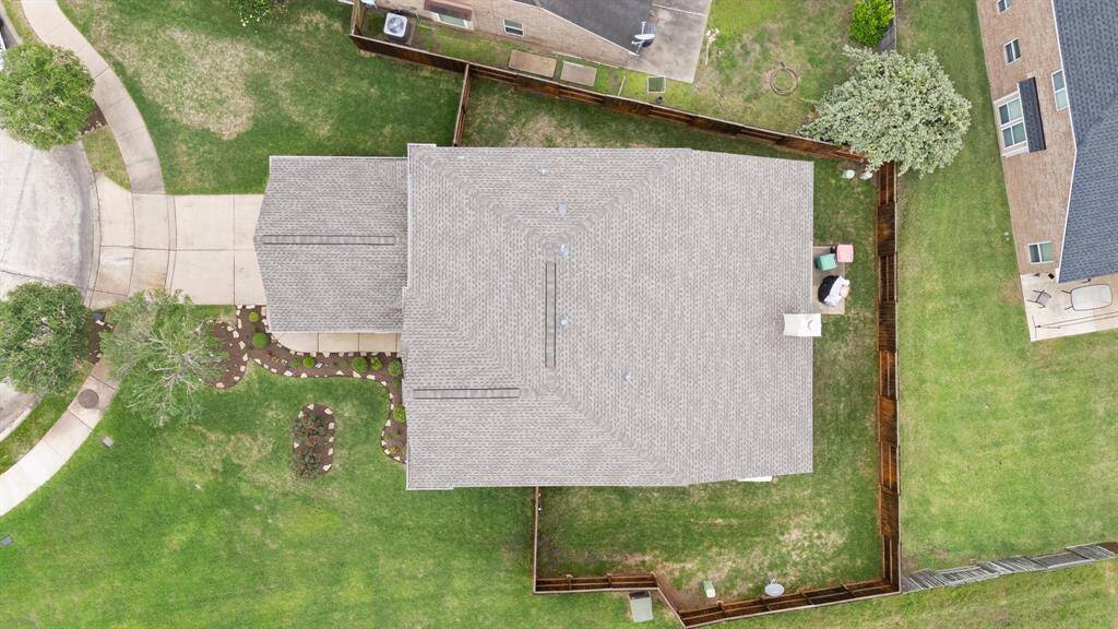 Bird’s eye view showcases the spacious fenced yard, thoughtfully landscaped front entry, and well-maintained roofline—ideal for outdoor enjoyment and future enhancements.