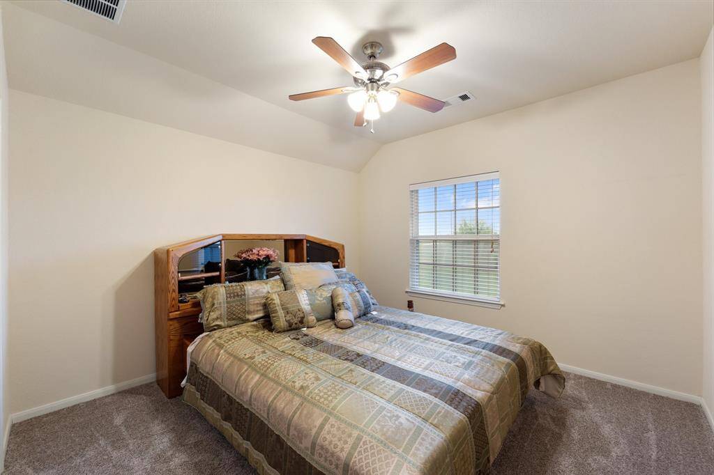 Secondary bedroom with vaulted ceilings, neutral walls, and a large window that brings in natural light.