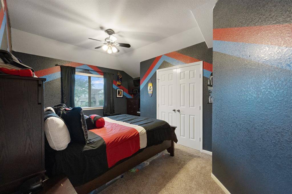 Secondary bedroom featuring a ceiling fan, generous closet space, and a large window.
