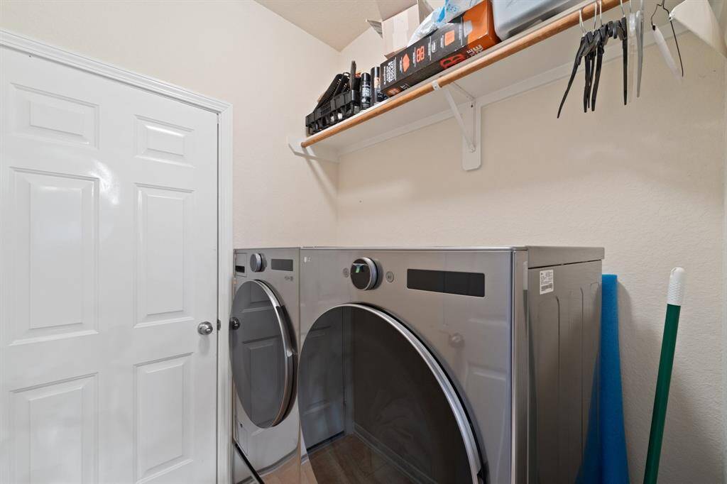 Convenient laundry room with upper shelving for storage and organization, plus space for full-size appliances and easy access from the main living areas.