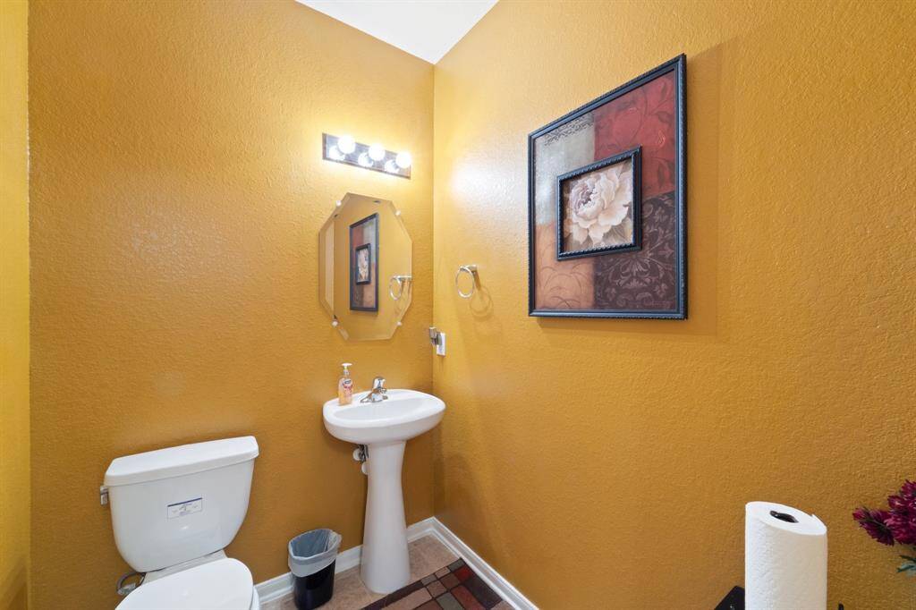Stylish powder bath with rich wall color, pedestal sink, and framed accent art—ideal for guests.