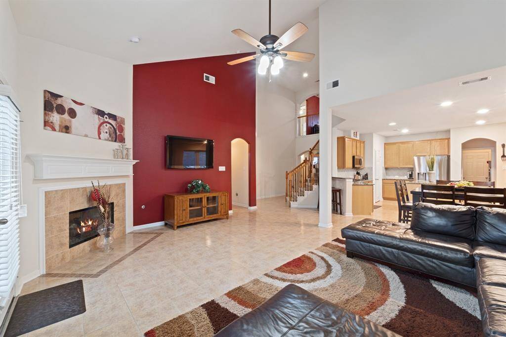 View from the living area showcases soaring ceilings, a bold accent wall, and seamless flow into the kitchen and staircase.