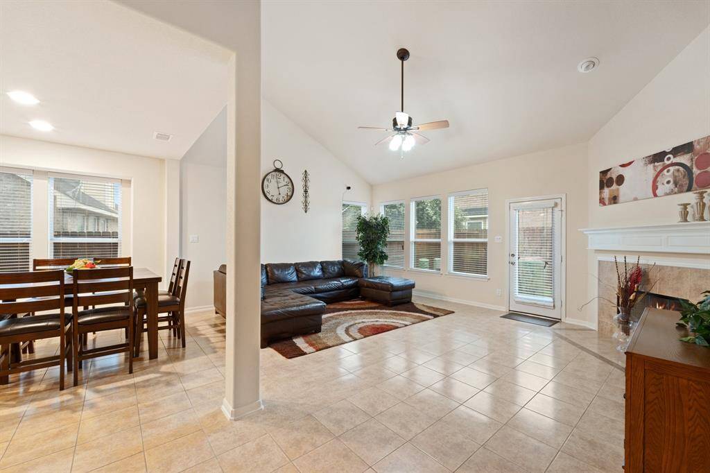 Spacious open-concept living and dining area with vaulted ceilings and tile flooring—flooded with natural light from multiple windows.