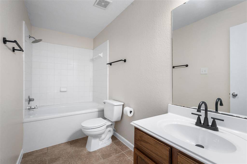 Your primary bathroom has a clean design with a tiled shower-soaking tub combo, modern fixtures, and a vanity with a large mirror. Neutral tones and tile flooring create a fresh and inviting space.