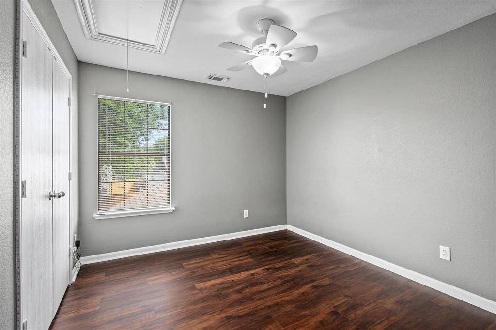 This bedroom has laminate flooring, and a ceiling fan. It includes a window for natural light and a closet with double doors creating a simple and inviting space.