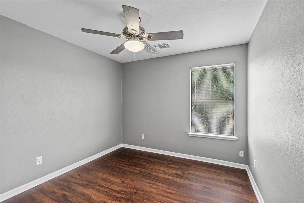 Another bedroom features a modern ceiling fan, and laminate flooring. A window provides natural light..