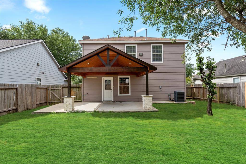 Another view of your backyard and attached covered patio. The patio features wooden beams and stone pillars, making this a cozy outdoor space. The yard is enclosed with a wooden fence making this a perfect setting for outdoor activities.