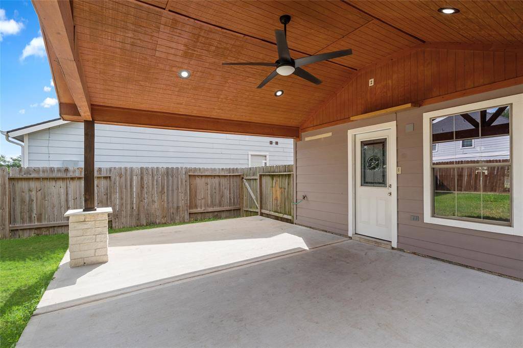 Your new covered patio has a wooden ceiling and ceiling fan, perfect for outdoor relaxation. It has a concrete floor and direct access to the house via a stylish door with a decorative glass panel.