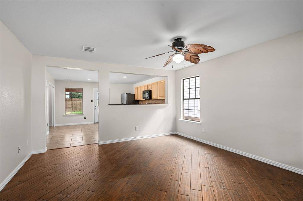 You will love your bright, open living area with wood-look tile flooring and neutral walls. The ceiling fan with leaf-shaped blades add a touch of class. A pass-through window to a kitchen enhances the open feel of the space. A large doorway allows a view of the backyard through the dining room window.