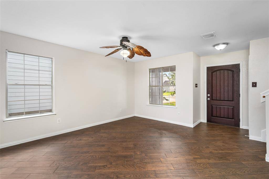 Your new living room has ample natural light from two windows, and the dark wooden front door creates a welcoming entryway.