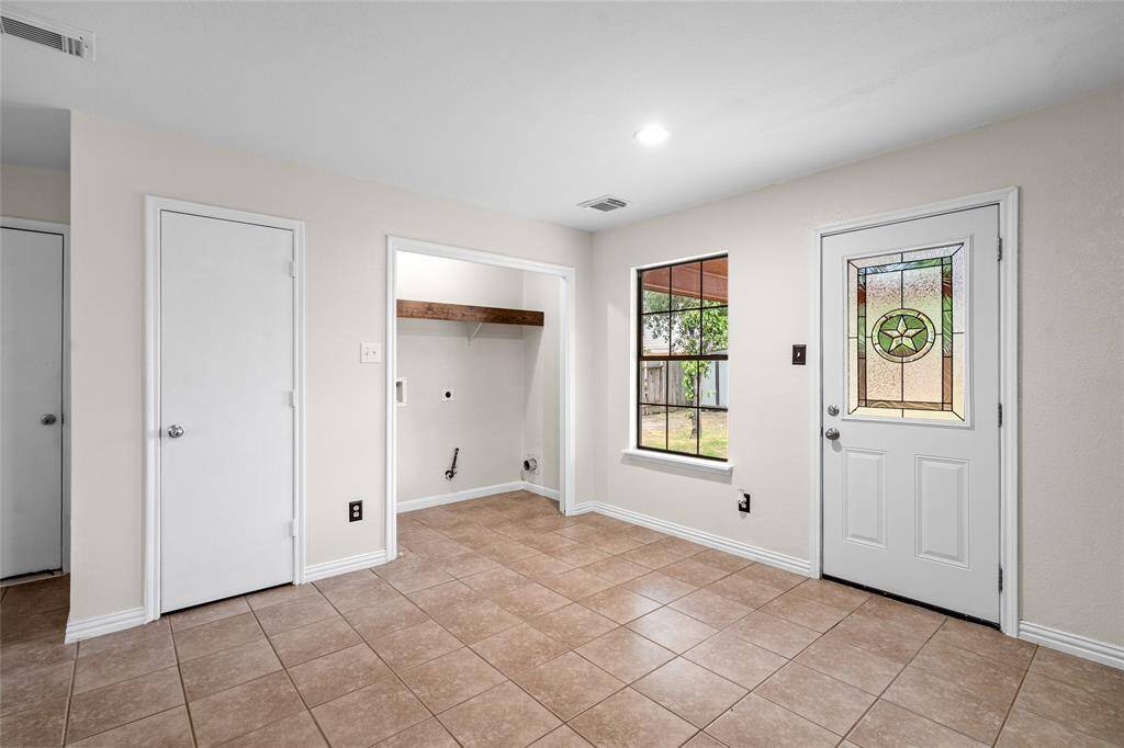 Your convenient dining room has tile flooring and features a convenient laundry area. The window offers a view of the backyard, and an exterior door has Texas themed decorative glass.