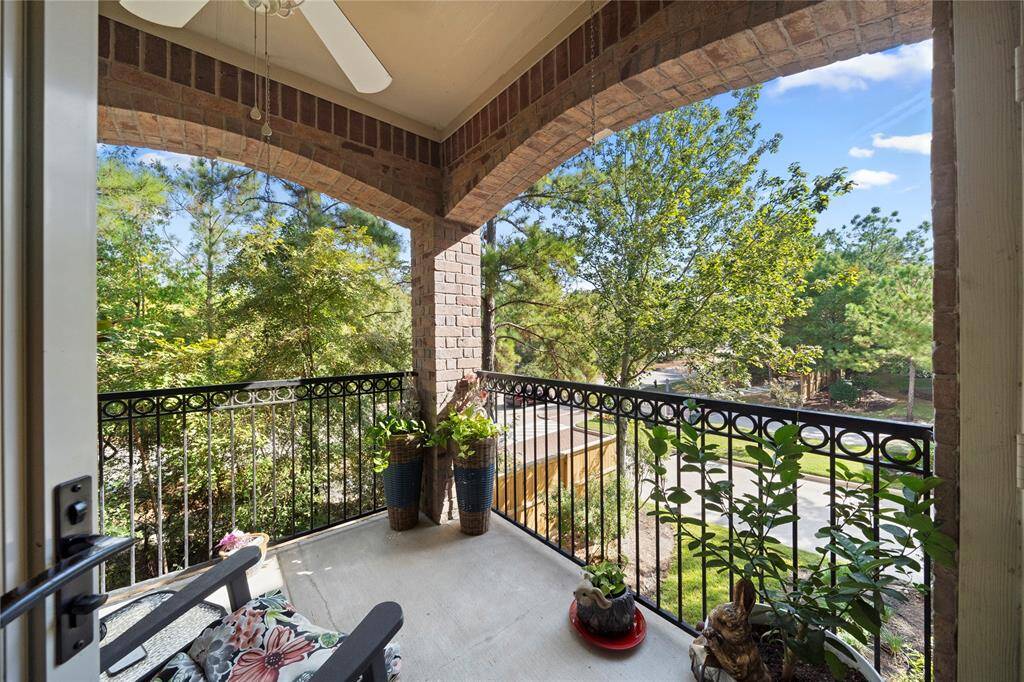 This is a cozy, covered balcony with a wrought iron railing, offering a pleasant view of greenery and a residential street. It's a tranquil space to enjoy the outdoors with some privacy.