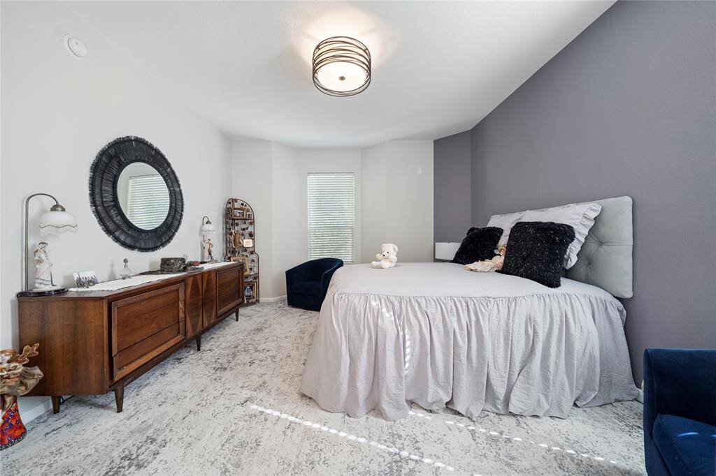 The room has a neutral color palette with contrasting dark blue accents, carpeted flooring, and a contemporary ceiling light fixture.
