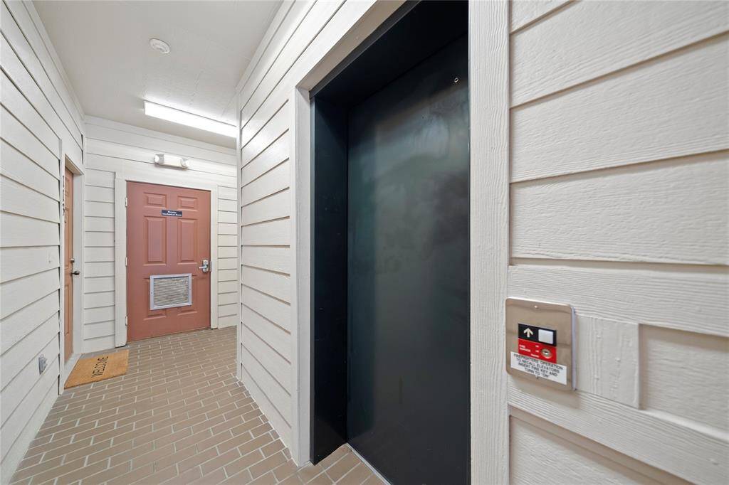 This is a secure, well-lit entryway featuring a herringbone patterned tile floor, a neutral color scheme, and an elevator for easy access to upper floors.