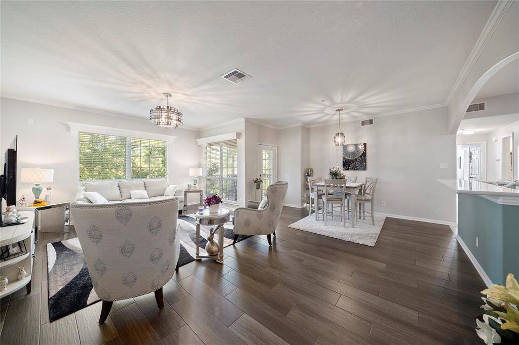 This is a bright and spacious open-concept living and dining area with elegant hardwood floors, large windows for ample natural light, and modern light fixtures. The space is well-appointed and move-in ready.
