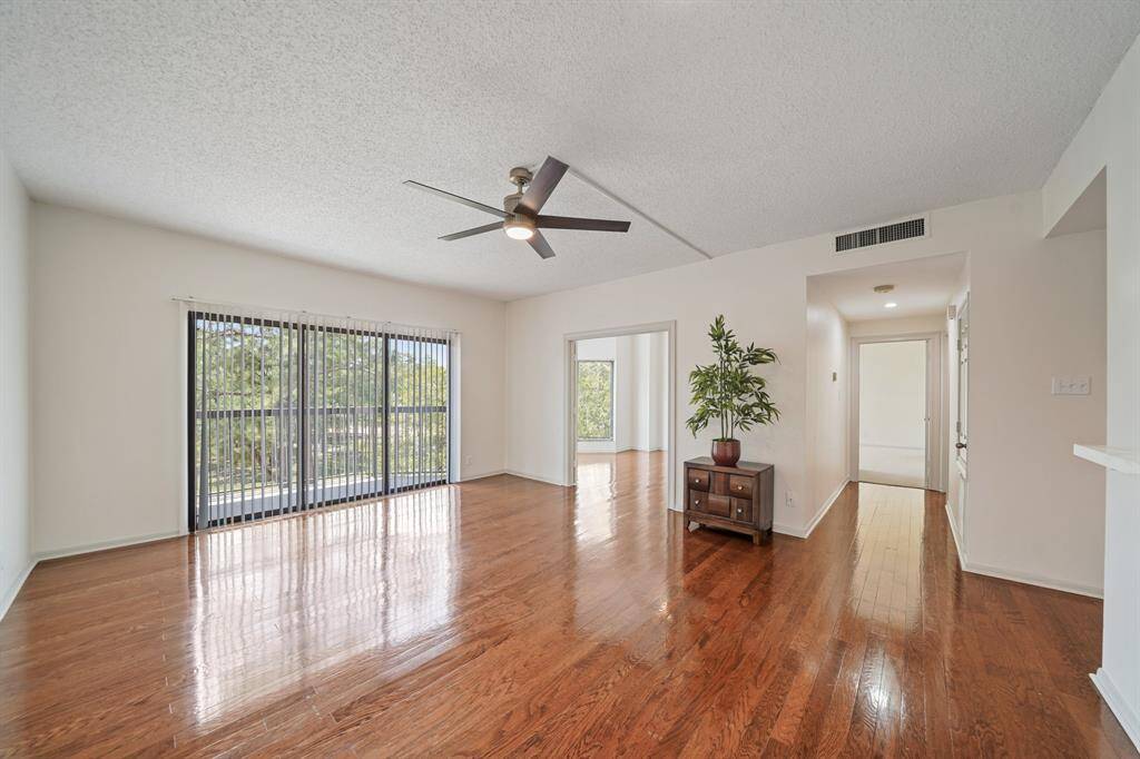 The expansive living room and a balcony just beyond the vertical blinds.