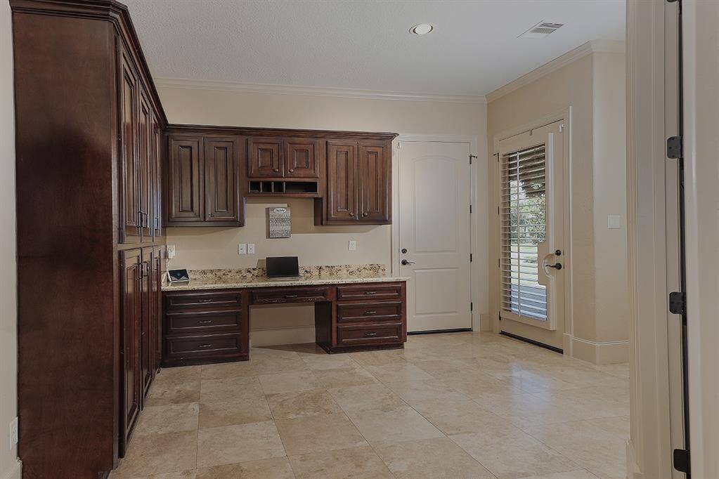 Thoughtful mud room with desk and custom cabinetry with access to split garages
