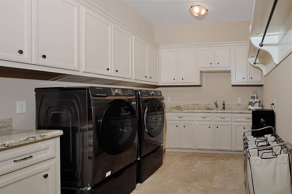 Generous utility room with custom cabinets and useful utility sink