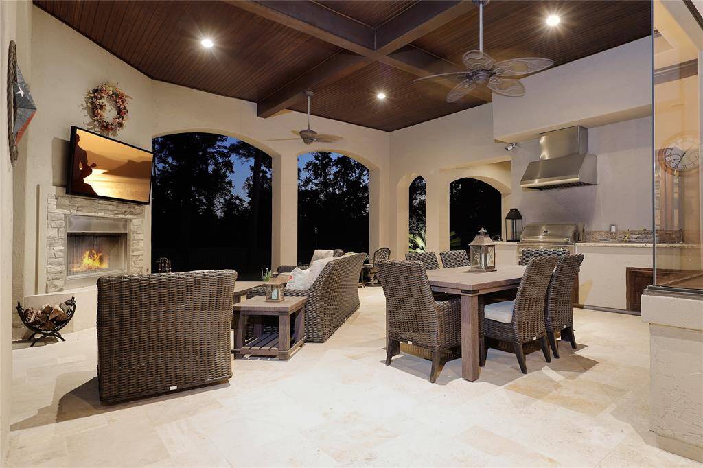 Spacious covered patio hosts outdoor kitchen, cozy fireplace, living and dining areas