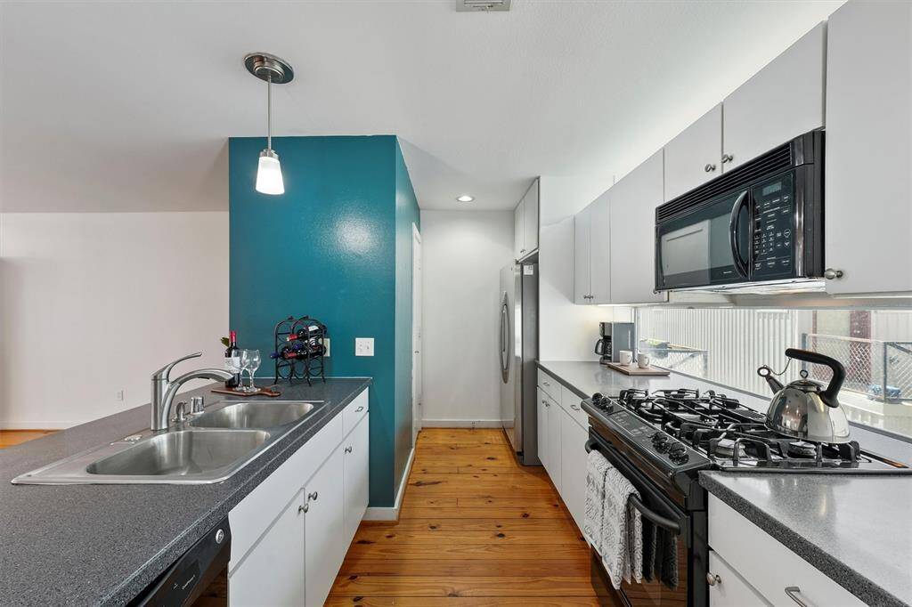 The kitchen has a window wall above and below the upper cabinets for even more light. Granite countertops, sink and faucet installed in 2023. Gas range and built-in microwave. Pantry.