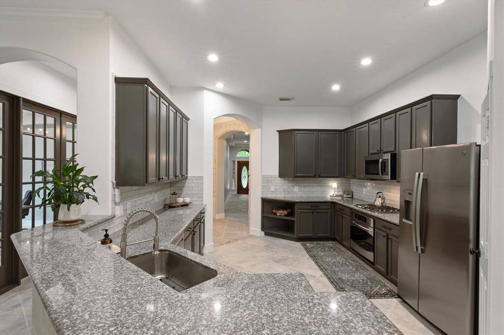 Just beyond the entryway lies the heart of the home—this stunning kitchen offers a spacious, open layout designed for seamless entertaining. Highlights include an abundance of custom cabinetry, luxurious Silestone countertops, a chic subway tile backsplash, and much more!