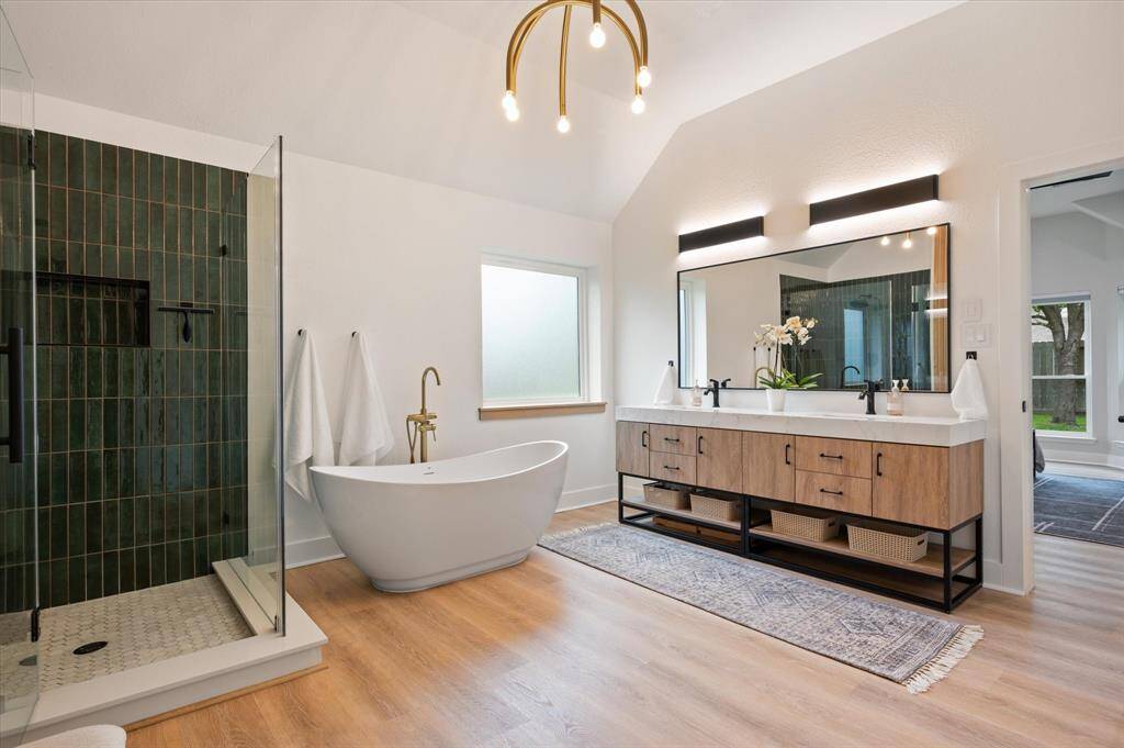 Take in the generous space of this luxurious primary bathroom! A distinctive lighting fixture adds a touch of personality and elegance, enhancing the overall ambiance of this thoughtfully designed retreat.