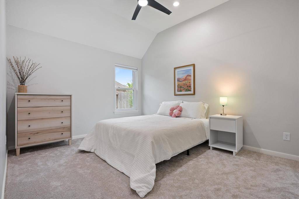 This secondary bedroom combines comfort and style, featuring plush carpeting installed in 2025, a soaring ceiling, and sophisticated decorator paint. Additional highlights include a spacious closet, a ceiling fan, and a bright window that fills the room with natural light.