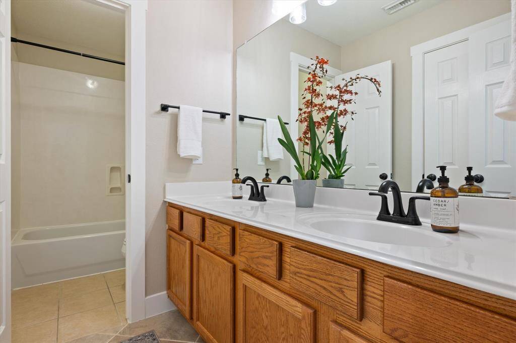 The full bathroom boasts a spacious vanity with dual sinks, sleek countertops, and a tub/shower combination—combining style and functionality, perfect for both family and guests.