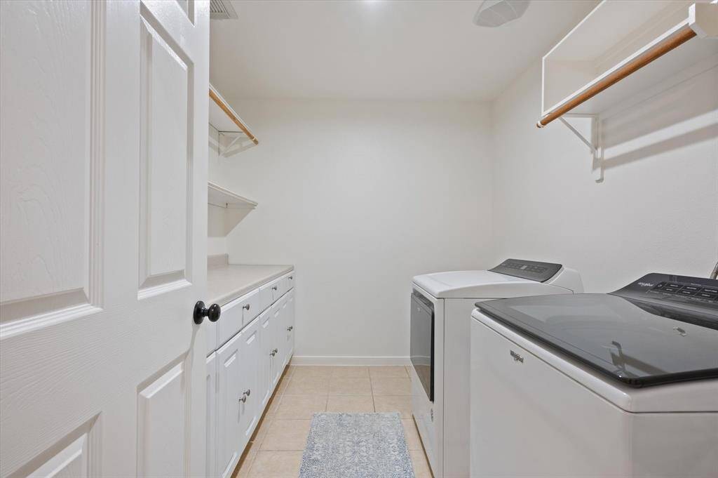 The spacious utility room is thoughtfully designed with shelving, hanging racks, cabinetry, and a countertop, making it ideal for all your laundry needs. Plus, there’s ample space for an additional refrigerator if desired.