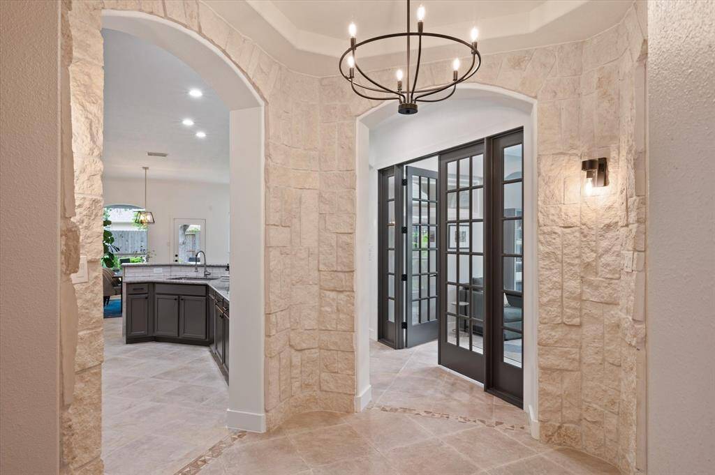 Just beyond the entryway, a striking stone-accented rotunda creates a dramatic architectural focal point. Overhead, a beautiful chandelier paired with an elegant tray ceiling adds depth and sophistication to this impressive space. Through the beutiful doors to the right, you'll find your private study.