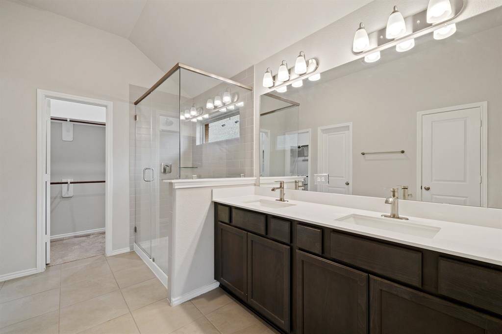 Primary bathroom with dual sinks, separate oversized shower, and a good amount of storage space.
