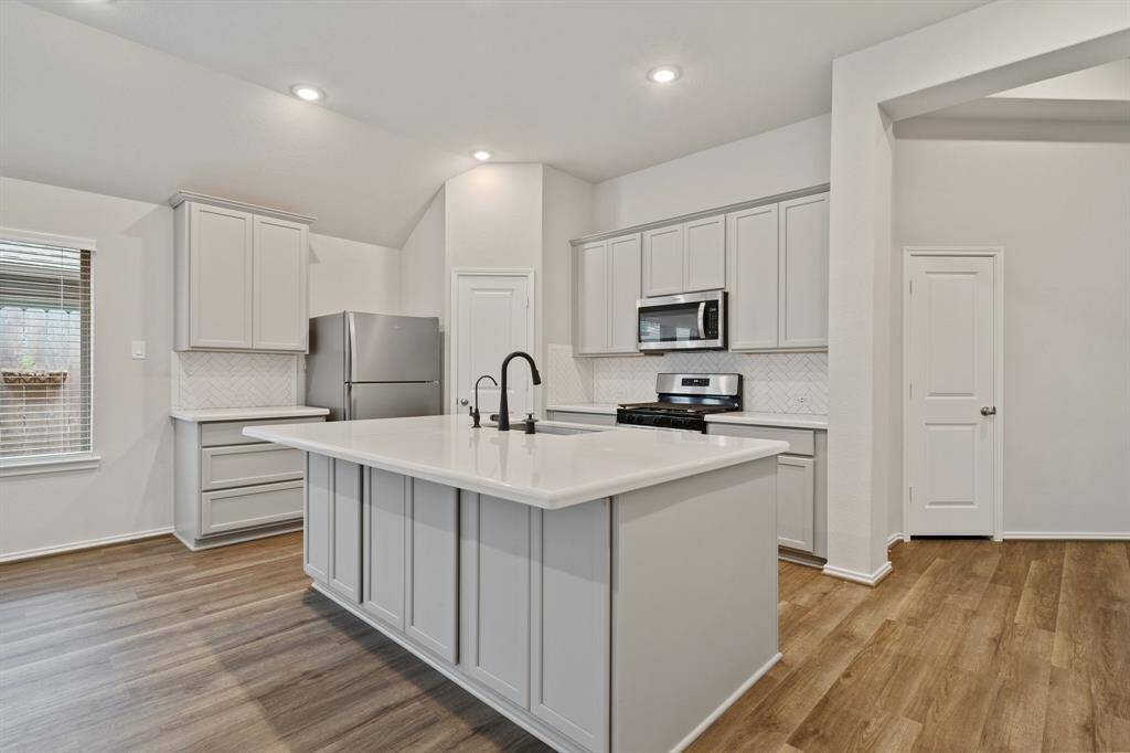 Gorgeous modern kitchen with quartz countertops, sleek cabinets, stainless steel appliances, and breakfast bar.