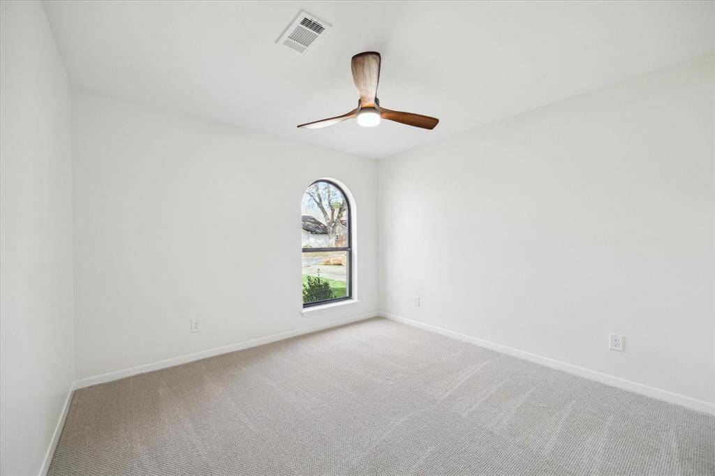 Bright bedroom with a ceiling fan and abundant natural light.