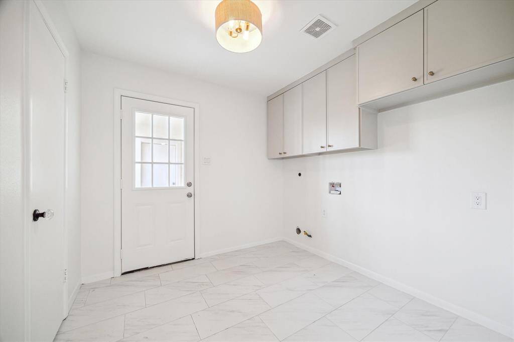 Functional laundry/utility room with ample cabinets and elegant gold lighting.