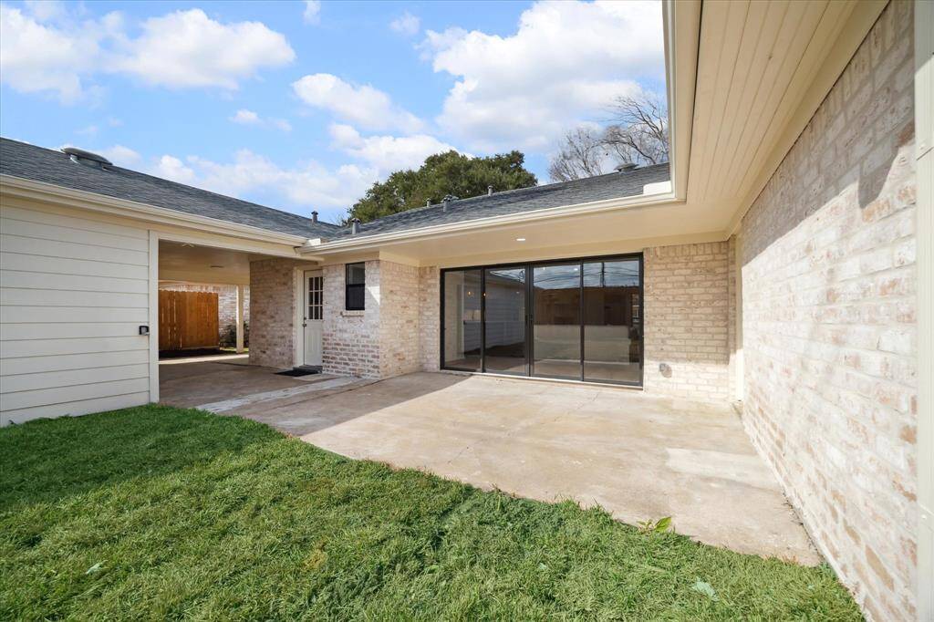 Expansive backyard with new sod and landscaping, a 12' wide glass sliding door leading to the living area, and a spacious patio.