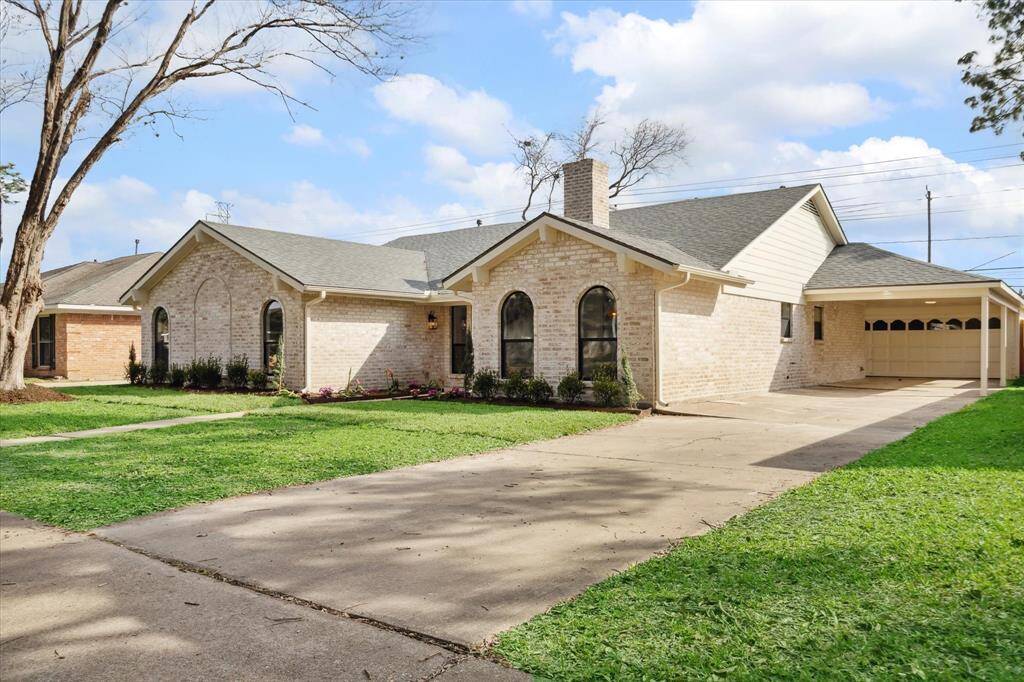Elegant front view with new sod, lush landscaping, and a spacious driveway.