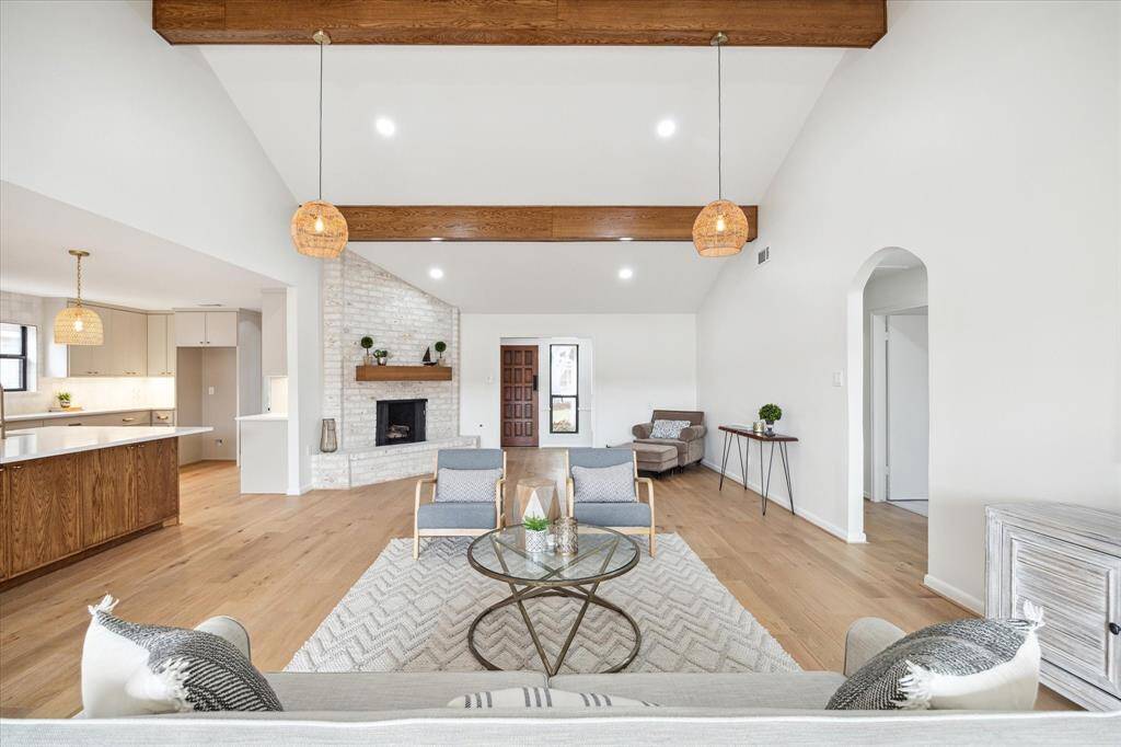Warm and inviting living/kitchen area with a fireplace, rattan lighting, and engineered white oak floors.
