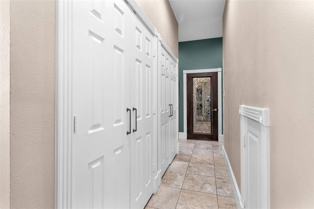 Hallway leading to kitchen with 2 large custom built butler's pantry closets. Luggage storage under the stairs.