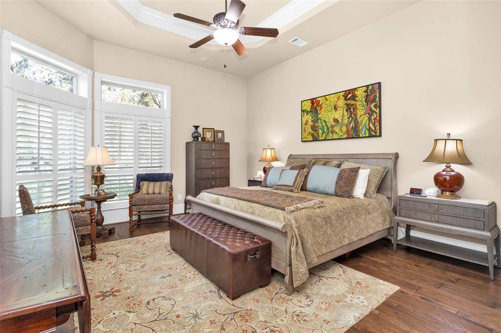 Primary bedroom with wood floors & sitting area faces the manicured back yard